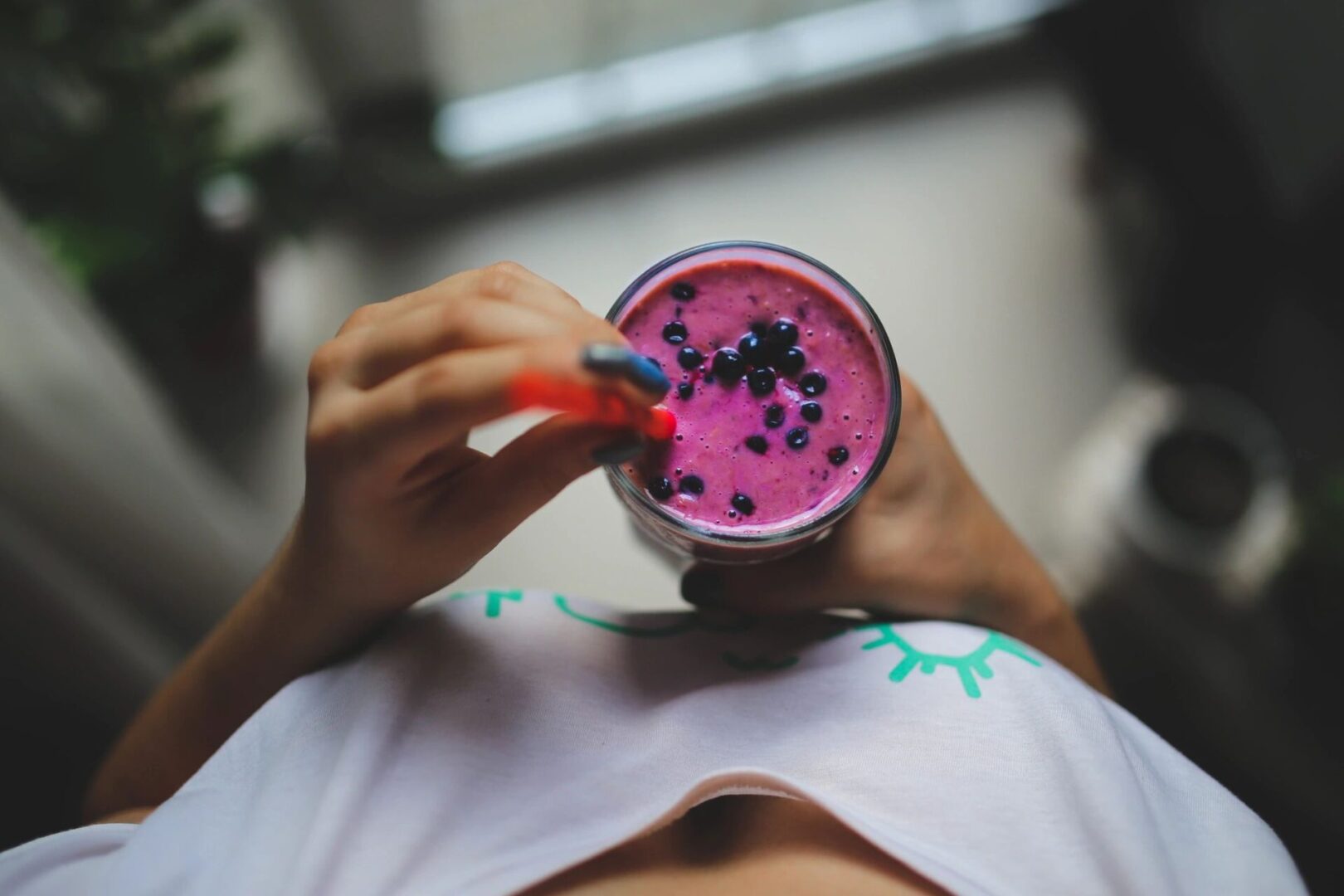 A person holding a cup of fruit smoothie.