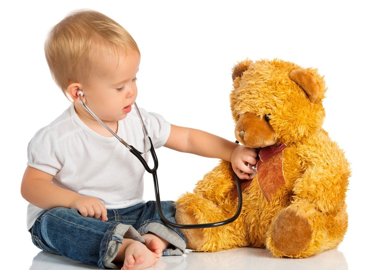 A little boy is playing with a teddy bear.