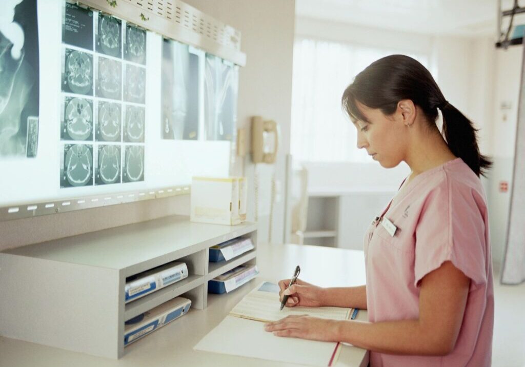 Doctor writing notes in front of x-ray images.